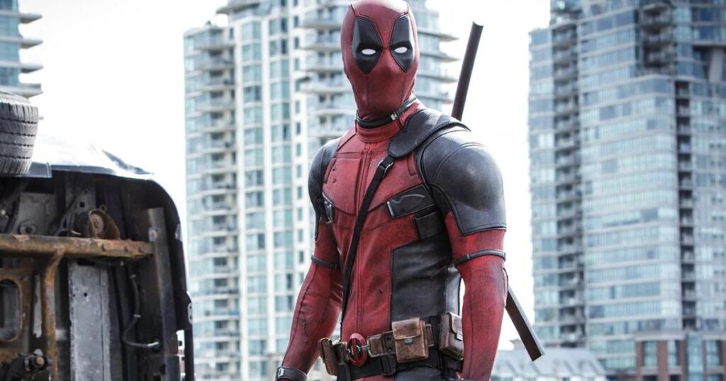 A close-up side profile of the character Deadpool in his signature red and black tactical suit, looking toward the right with a blurred background.