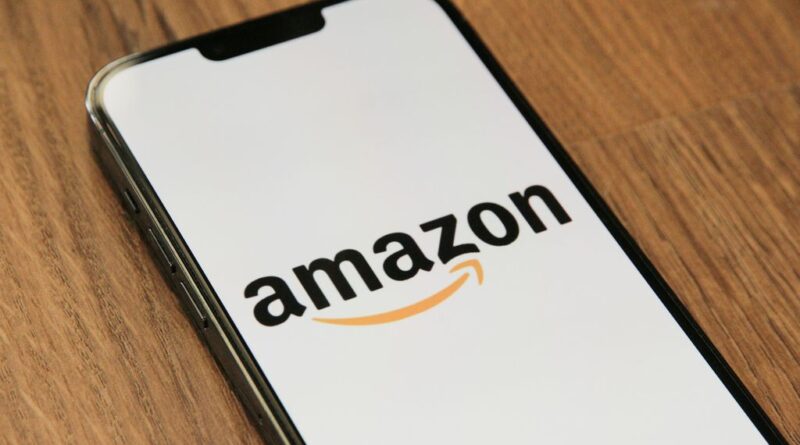 A smartphone on a wooden table displaying the Amazon logo, representing new AI voice shopping features.