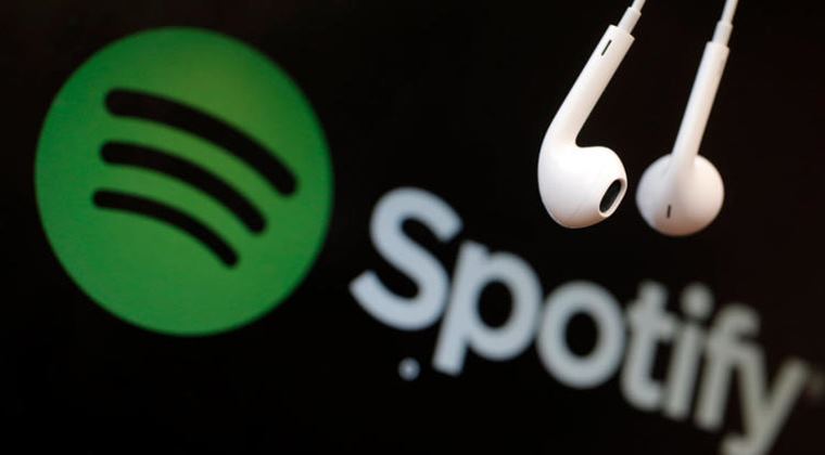 The white Spotify logo on a green background alongside a pair of white wired earphones on a black background.