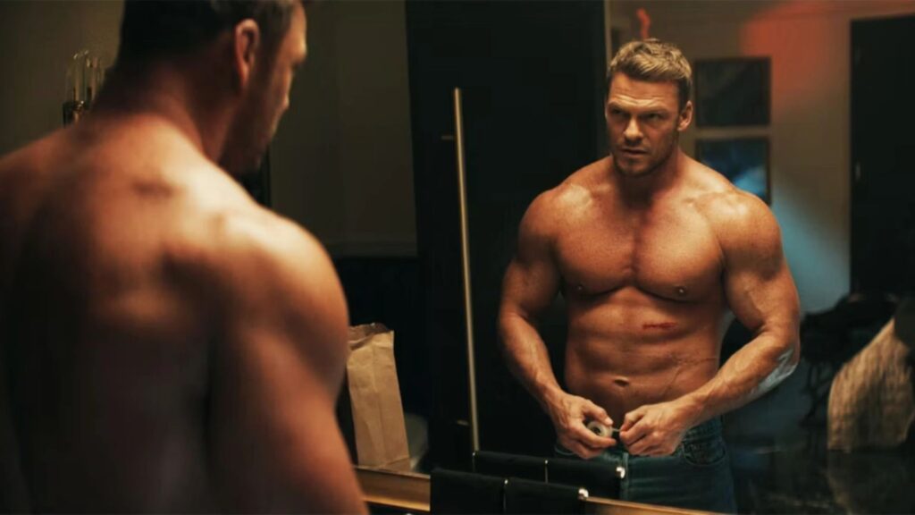 Alan Ritchson in a dramatic scene from the Prime Video series Reacher, showcasing the physical intensity of the character Jack Reacher.