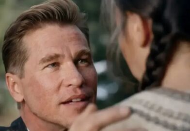 A close-up shot of Val Kilmer looking intently with an emotional expression, with another character's back in the foreground.