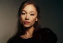 Close-up portrait of singer Ariana Grande looking at the camera with dark hair and a neutral expression.