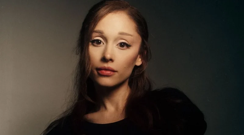 Close-up portrait of singer Ariana Grande looking at the camera with dark hair and a neutral expression.