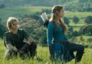 Live-action portrayal of Link and Princess Zelda, played by Benjamin Evan Ainsworth and Bo Bragason, kneeling in a lush green field in a cinematic scene from the upcoming movie.