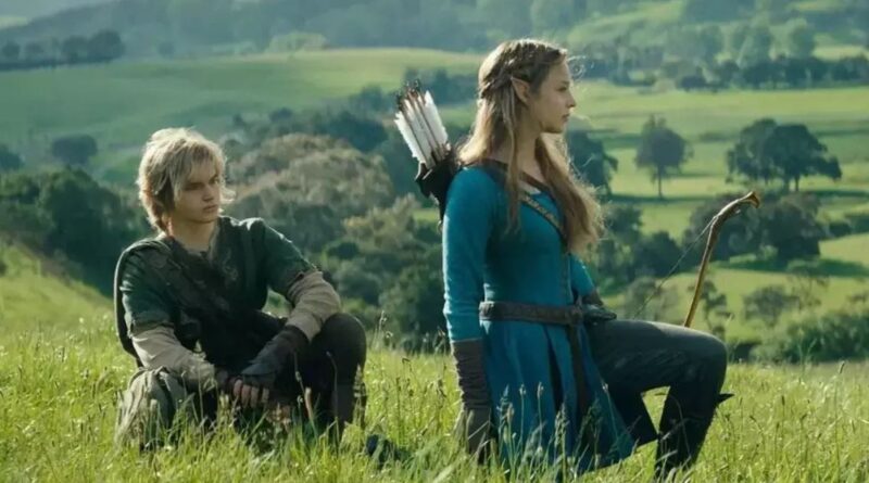 Live-action portrayal of Link and Princess Zelda, played by Benjamin Evan Ainsworth and Bo Bragason, kneeling in a lush green field in a cinematic scene from the upcoming movie.