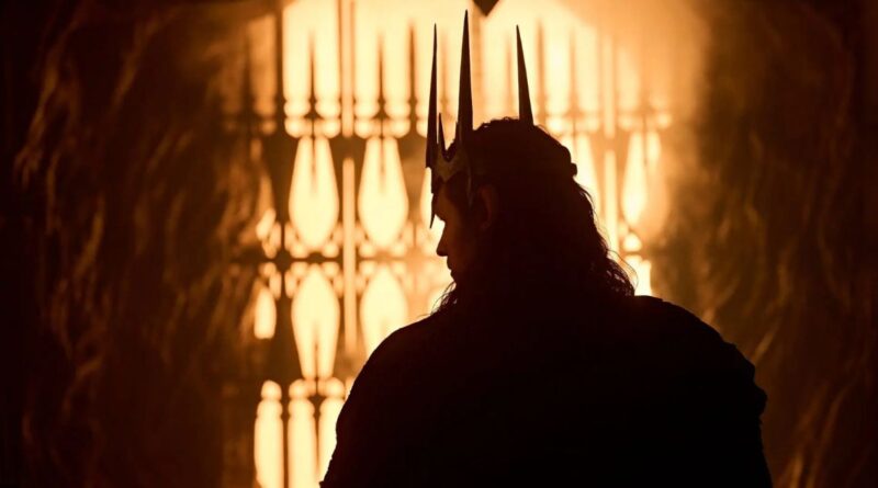 Silhouette of Charlie Vickers as Sauron wearing a spiked crown, standing before a glowing, fiery gate in a scene from The Rings of Power Season 3.