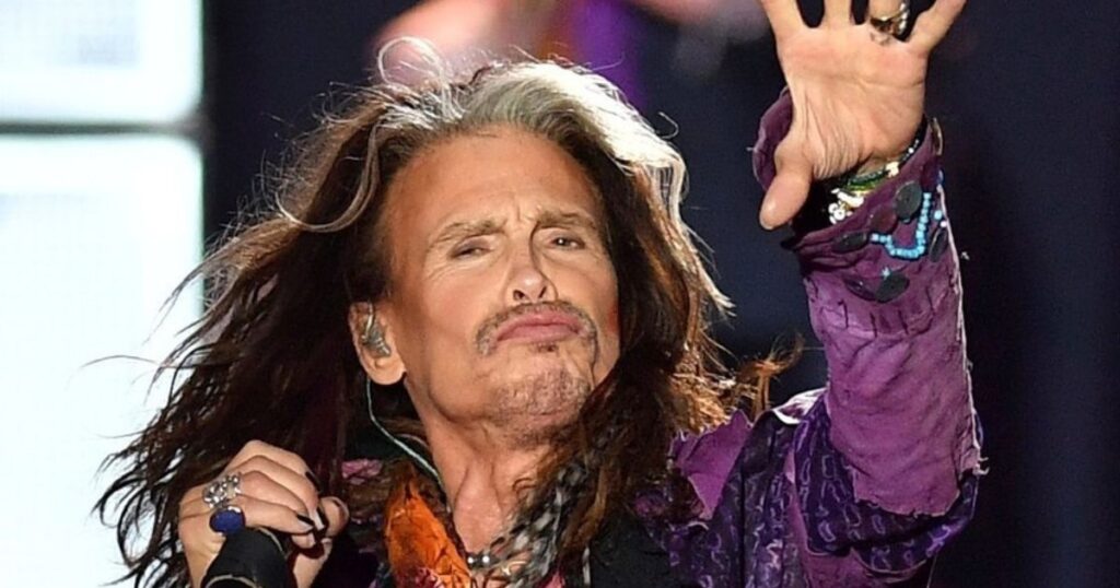 Close-up portrait of Steven Tyler, Aerosmith's lead singer, looking at the camera with a serious expression and his signature long hair.